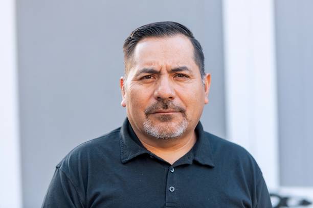 Contact hispanic mature man posing looking at the camera at his home backyard